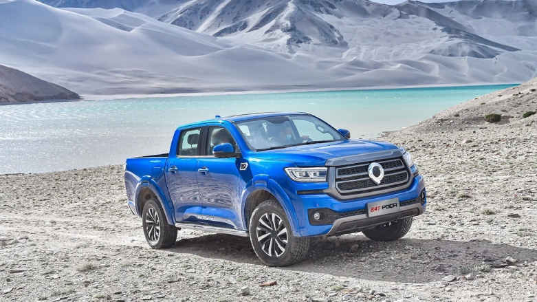Camioneta pick-up GWM Poer Passenger color azul siendo conducida sobre terreno rocoso con lago de fondo.